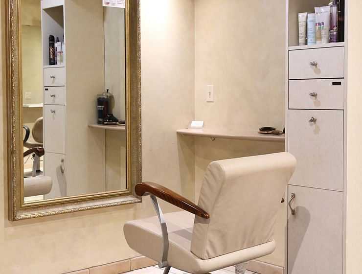 A salon interior with a chair facing a mirror and products on shelves.